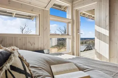 a bedroom with a bed and large windows at Hedda Lenningen - 3 bedroom cabin with view towards Langsua National Park in Etnedal