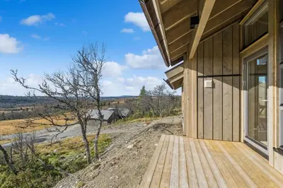 a wooden walkway leading to a house with a view at Hedda Lenningen - 3 bedroom cabin with view towards Langsua National Park in Etnedal
