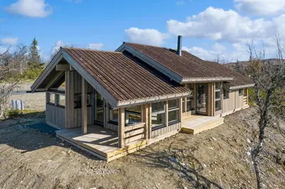 a small house with a brown roof on a field at Hedda Lenningen - 3 bedroom cabin with view towards Langsua National Park in Etnedal