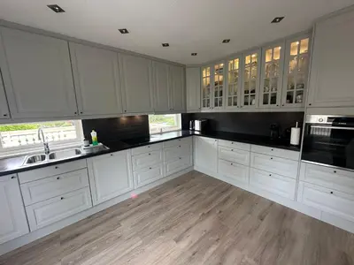 a kitchen with white cabinets and a wooden floor at Flott bolig på Øvre kleppe med fine solforhold og fin uteplass in Askøy