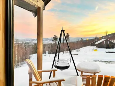 a porch with a swing and chairs in the snow at Cabin at Norefjell ski resort, nice view in Noresund