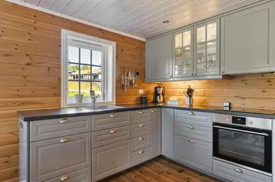 a kitchen with white cabinets and wooden walls at Solsiden 16B by Vacation Trysil in Trysil