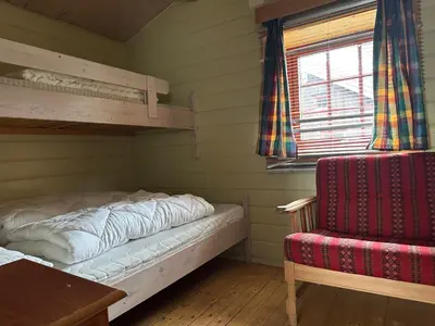a bedroom with a bed and a chair and a window at Bjorliheimen Fjellhotell-Hytte 9 in Bjorli