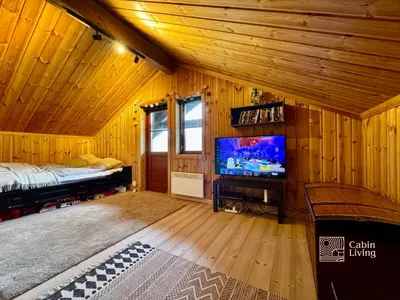a room with a bed and a tv in a cabin at Modern cabin sauna, BBQ & beautiful view Filefjell in Tyinkrysset