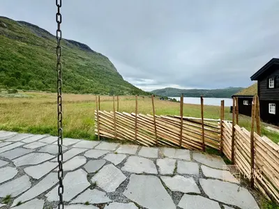 a swing in front of a fence and a field at Modern cabin sauna, BBQ & beautiful view Filefjell in Tyinkrysset