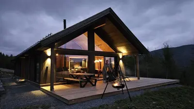 a small cabin with a wooden deck in the woods at Spacious lodge with sauna, ski centre in Noresund
