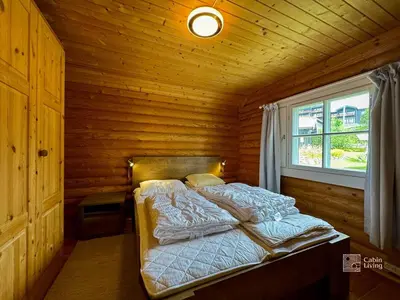 a bed in a wooden room with a window at Beitostølen Cabin - Sauna, large terrace and BBQ in Beitostøl