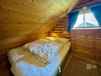 a bed in a wooden room with a window at Beitostølen Cabin - Sauna, large terrace and BBQ in Beitostøl