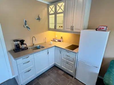 a kitchen with white cabinets and a white refrigerator at 8 person holiday home in Urangsvåg in Ervik