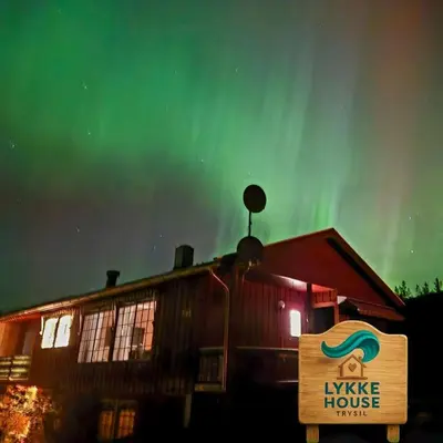 a sign in front of a house with a green sky at Lykke House Hot Tub, Grill Hut Northern Lights in Trysil