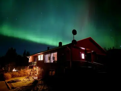 a house with the aurora in the sky at Lykke House Hot Tub, Grill Hut Northern Lights in Trysil