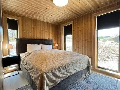 a bedroom with a bed in a room with windows at Skogsbu - Stylish, Close to Ski centers and hiking trails in Nesbyen