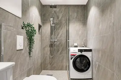 a washing machine in a bathroom with a shower at Light & Modern, City Apartment in Bergen