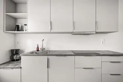 a kitchen with white cabinets and a sink at Light & Modern, City Apartment in Bergen