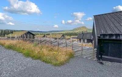 a row of barns and a fence with mountains in the background at Cozy Home In Svingvoll With House A Mountain View in Svingvoll