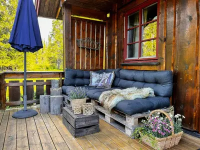 a blue couch sitting on a deck with an umbrella at Newly Renovated Cabin By Sjusjoen Ski Slopes in Sjusjøen