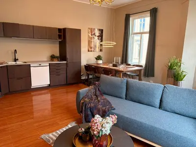 a living room with a blue couch and a kitchen at Charming apartment Nygårdsparken in Bergen