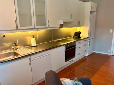 a kitchen with white cabinets and a sink at Apartment in apartment building, close to the train station in Bergen