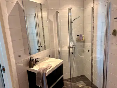 a white bathroom with a shower and a sink at Apartment in apartment building, close to the train station in Bergen