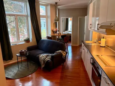 a living room with a couch and a table in a kitchen at Apartment in apartment building, close to the train station in Bergen