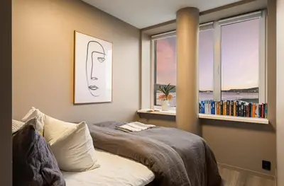 a bedroom with a bed and a window with books at Spectacular view 2 roms apartment in Bergen