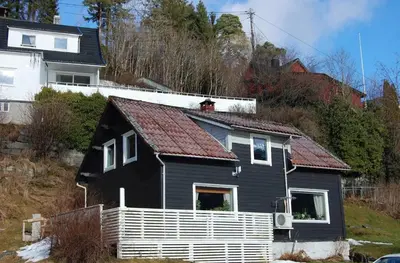 a black house with a red roof on a hill at Sauda 4 bedrooms near skiing with view of fjord in Sauda