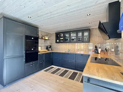 a large kitchen with blue cabinets and wooden floors at Bjørnebo, Family cabin in Torpo