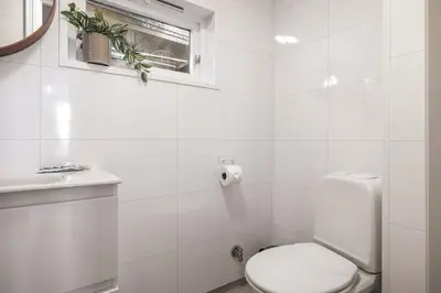 a white bathroom with a toilet and a window at Exclusive & Charming Apartment in Bergen