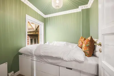 a bedroom with green walls and a bed with white sheets at Exclusive & Charming Apartment in Bergen