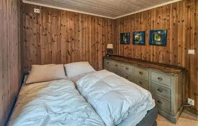 a bed in a bedroom with wooden walls and wooden cabinets at Amazing Home In Veggli With Wifi in Veggli