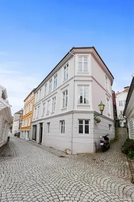 a large white building on a cobblestone street at Pepes Apartment in Bergen