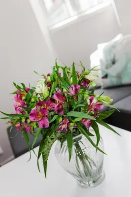 a glass vase filled with pink flowers on a table at Pepes Apartment in Bergen