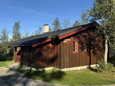 a small wooden cabin with a black roof at Briskebu, cosy cabin by ski slopes in Geilo