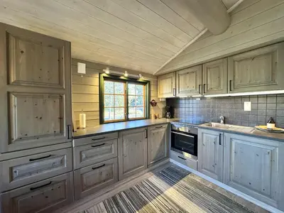 a large kitchen with wooden cabinets and a window at Briskebu, cosy cabin by ski slopes in Geilo