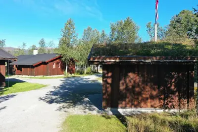 a dirt road next to a building with a flag at Tvilsombu, cosy cabin close to ski slopes in Geilo