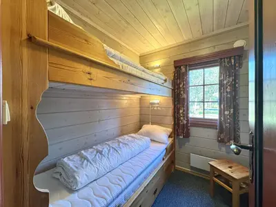 a room with a bed in a wooden cabin at Tvilsombu, cosy cabin close to ski slopes in Geilo