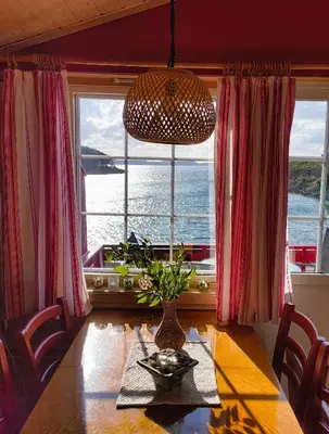 a dining room with a table and a large window at Retreat Øklandsnes in Lii