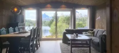 a living room with a table and a couch and a table and chairs at Renovated Cabin By Lake Djupedal in Bygstad