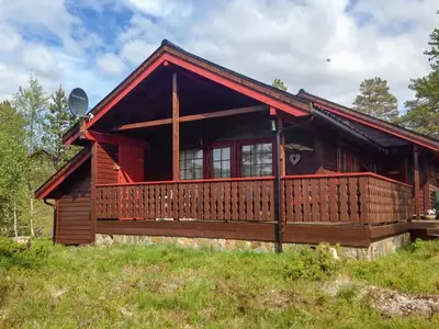 a log cabin with a large deck in a field at Renovated Cabin By Lake Djupedal in Bygstad