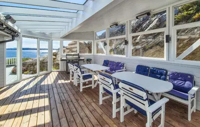 a porch with a table and chairs and the ocean at 4 Bedroom Gorgeous Home In Steinsland in Steinsland
