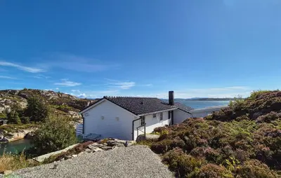 a white house on a hill next to the water at 4 Bedroom Gorgeous Home In Steinsland in Steinsland