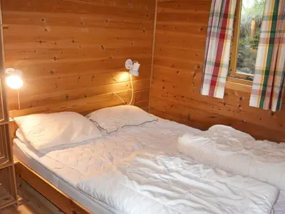 a bed in a room with a wooden wall at 6 person holiday home in Bud-By Traum in Bud