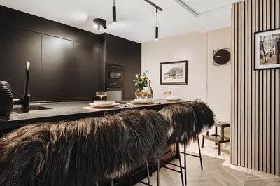 a kitchen with black cabinets and a table with fur chairs at Modern & Chic Apartment Luxurious Details in Bergen