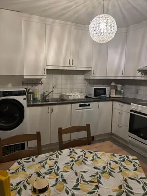 a kitchen with white cabinets and a table with chairs at Solsiden apartment in Sogndal