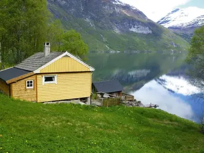 a yellow house on a hill next to a lake at 3 person holiday home in STRYN-By Traum in Stryn