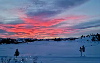 a sunset in a snowy field with a red sky at Family Cabin With Firepit At Søndre Fjellstølen in Reinli