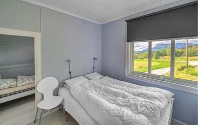 a bedroom with a bed and a chair and a window at 6 Bedroom Lovely Home In Holmedal in Holmedal