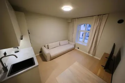 a small living room with a couch and a window at Cozy and practical studio in the city center in Ålesund