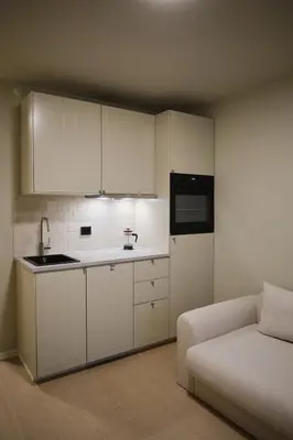 a kitchen with white cabinets and a couch in a room at Cozy and practical studio in the city center in Ålesund