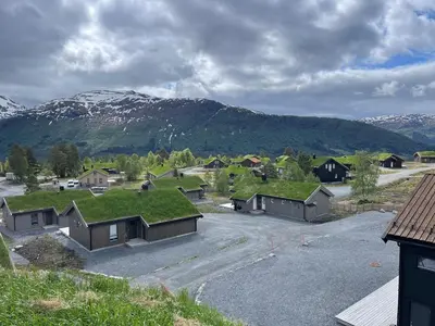 a group of houses with grass roofs with mountains in the background at Harevadet 217 in Volda